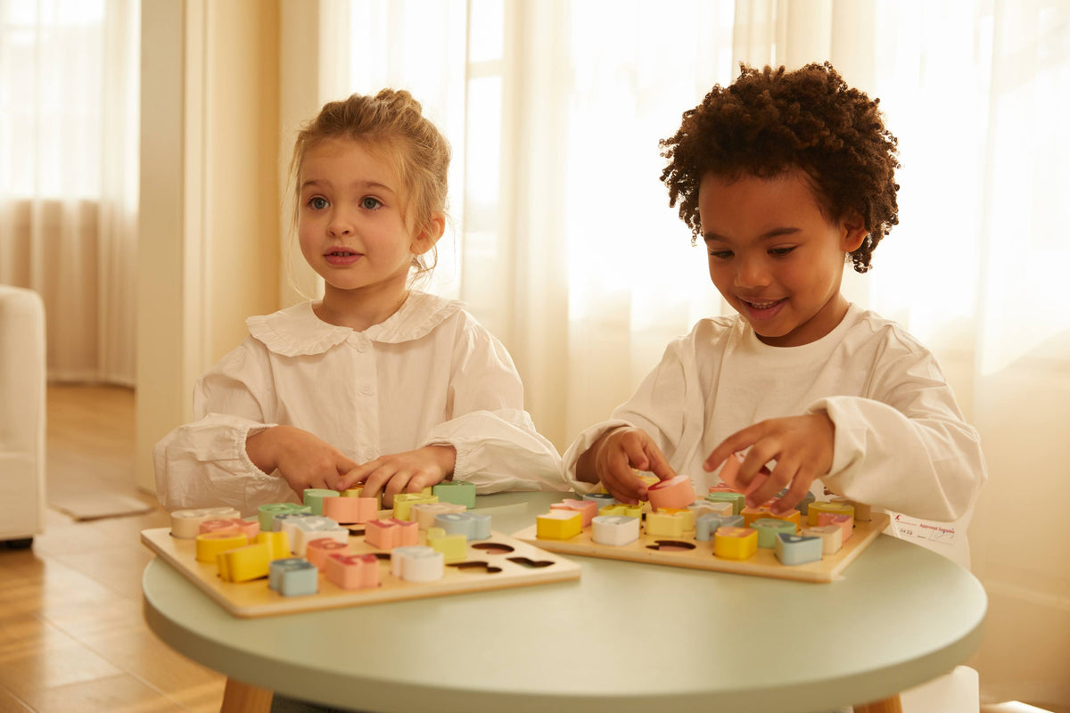 Two children playing with colorful toys on a table in a bright room.